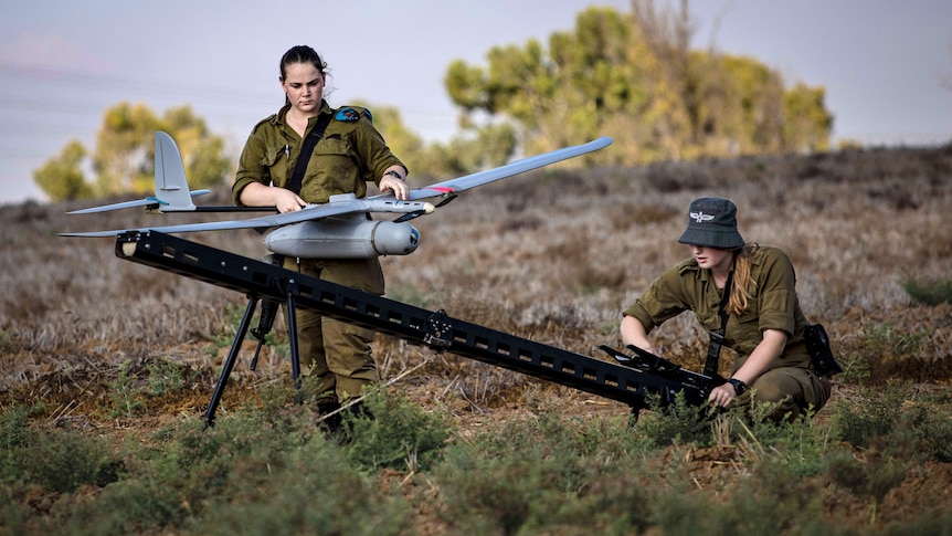 Two female soldiers inspect a drone 