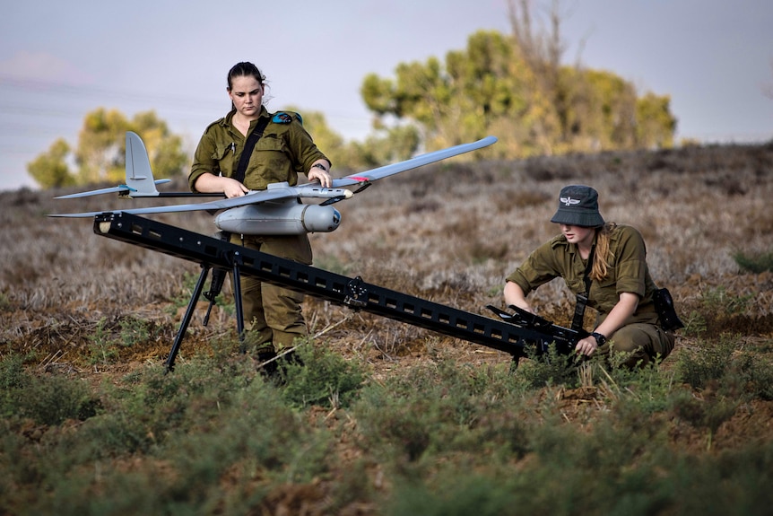 Two female soldiers inspect a drone 