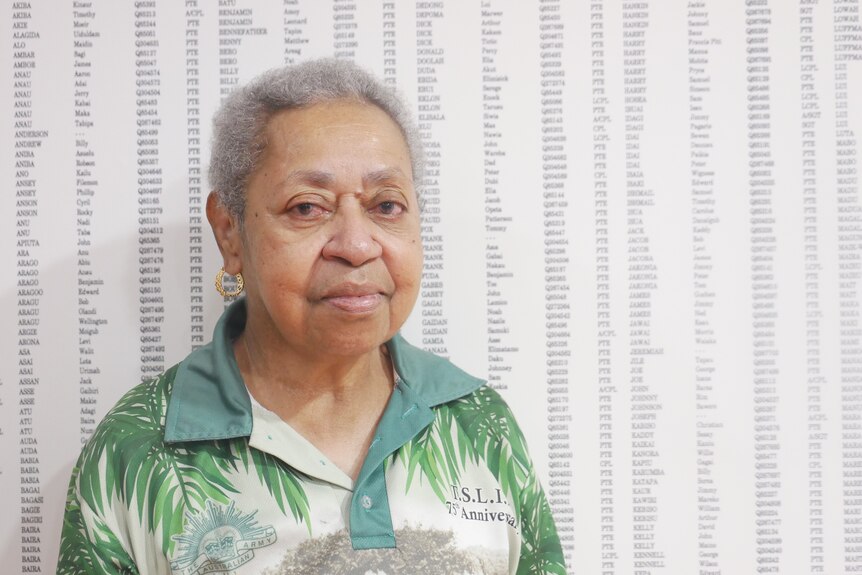 Torres strait Islander woman stands in front of military honour roll 
