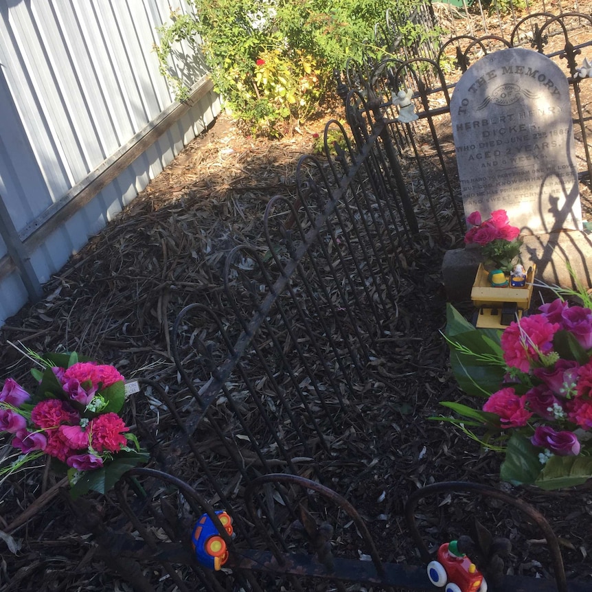 An old grave with bouquets of flowers and trucks on it