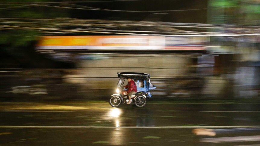 A man rides his tricycle as strong winds and rain from Typhoon Mangkhut batter Tuguegarao city