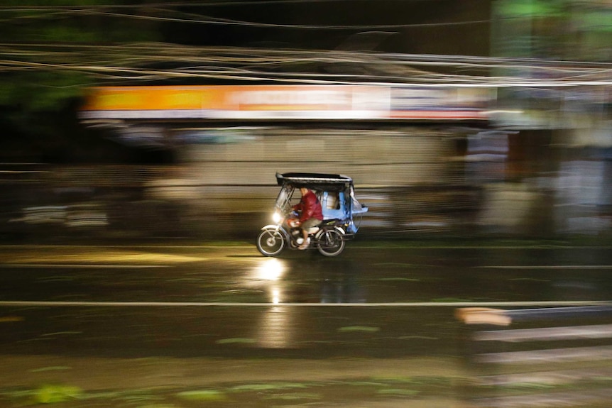 A man rides his tricycle as strong winds and rain from Typhoon Mangkhut batter Tuguegarao city