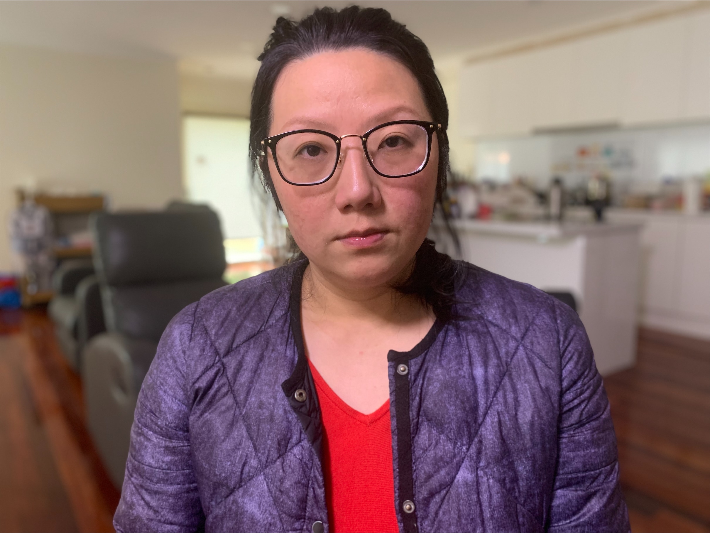 穿紫色夹克，戴黑色眼镜的亚洲妇女。