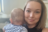 Woman holding baby with head turned away