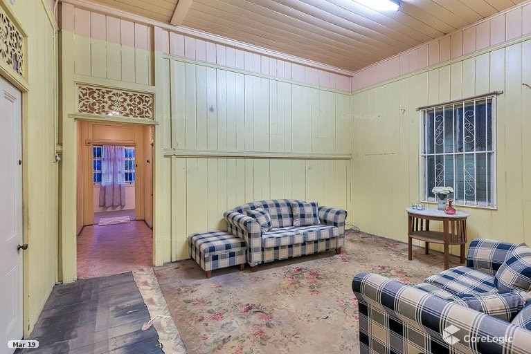 A lounge room with old floorboards and carpet, two shabby couches