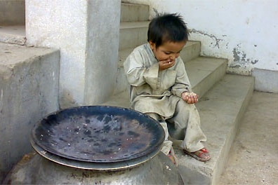 A child eats scraps of rice next to an empty rice bowl.