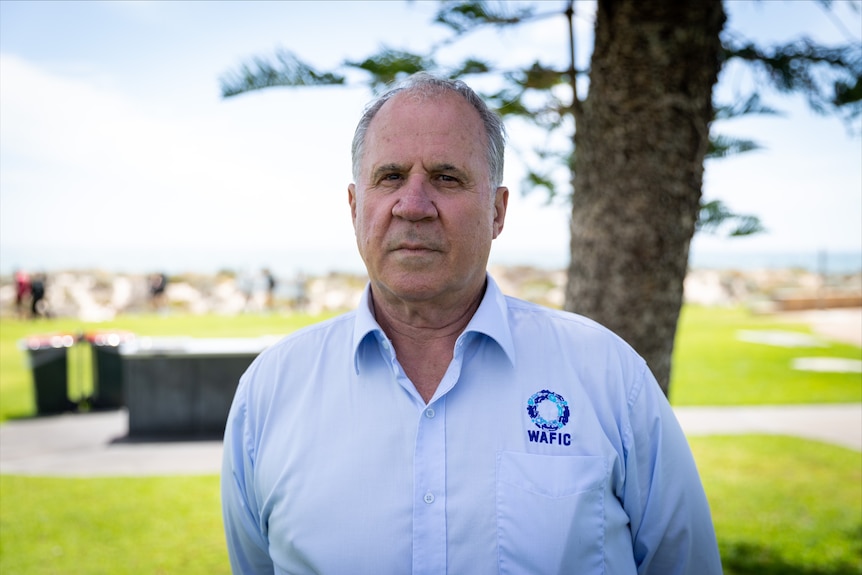 A man wearing a blue shirt looking serious. 