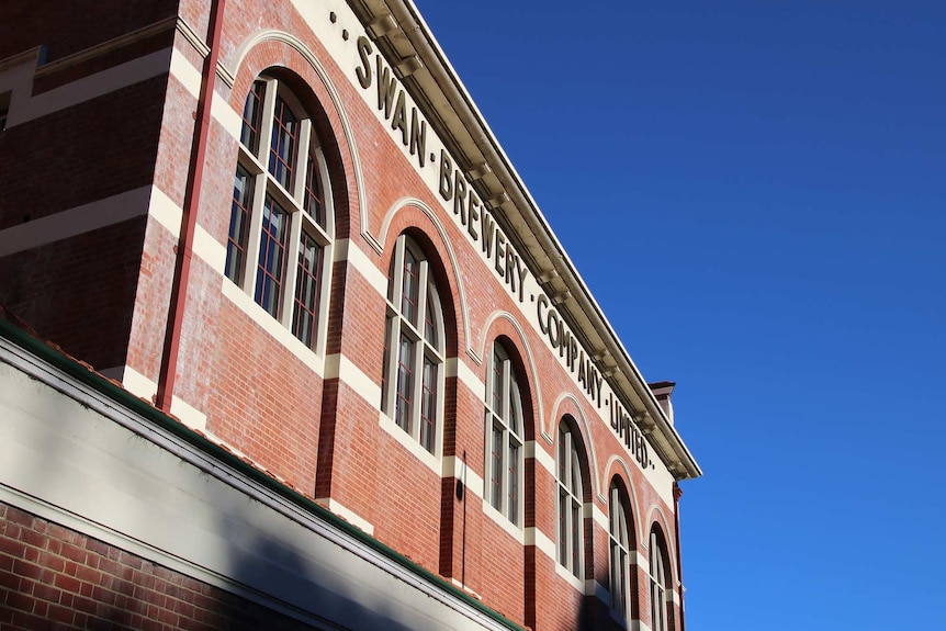 An angled shot of the top floor of the Old Swan Brewery brick building in Perth with a bright blue sky behind it.