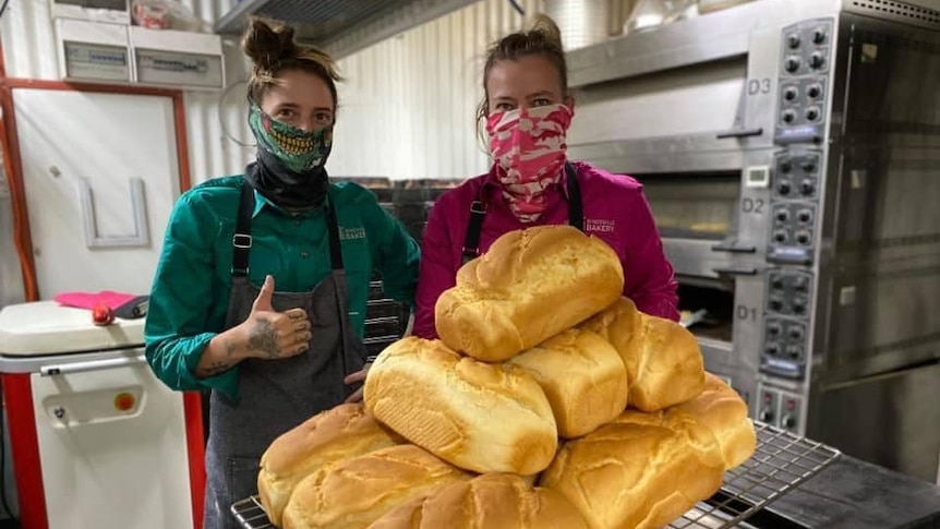 Two women with face masks behind bread