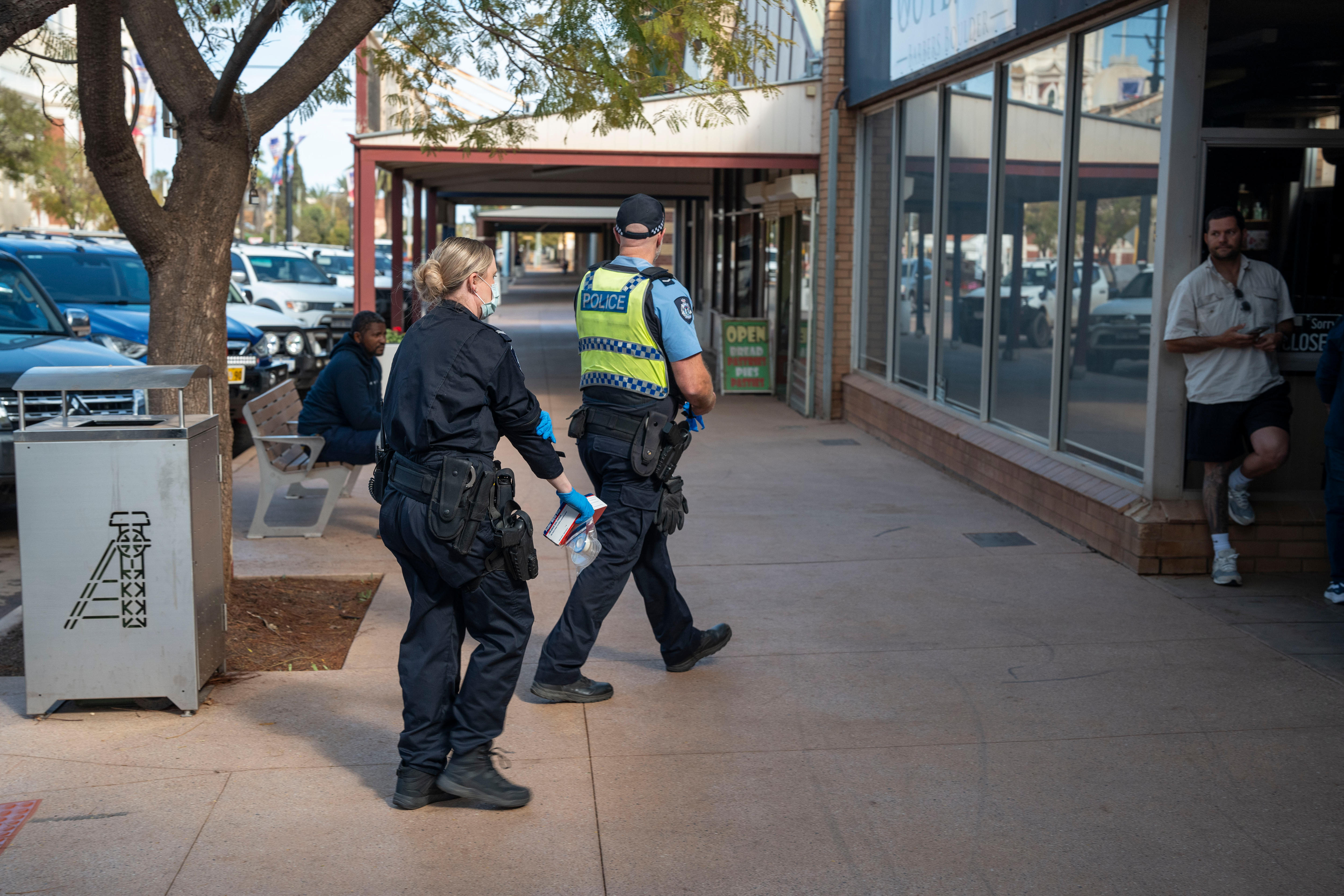 Two police walking on a footpath towards a building on Burt Street