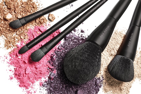 A collection of Mary Kay-branded brushes sit on top of powdered makeup.