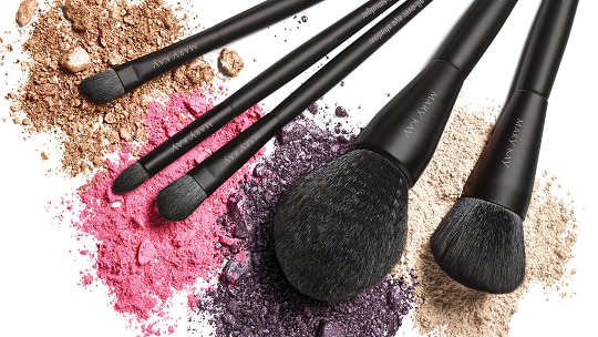A collection of Mary Kay-branded brushes sit on top of powdered makeup.
