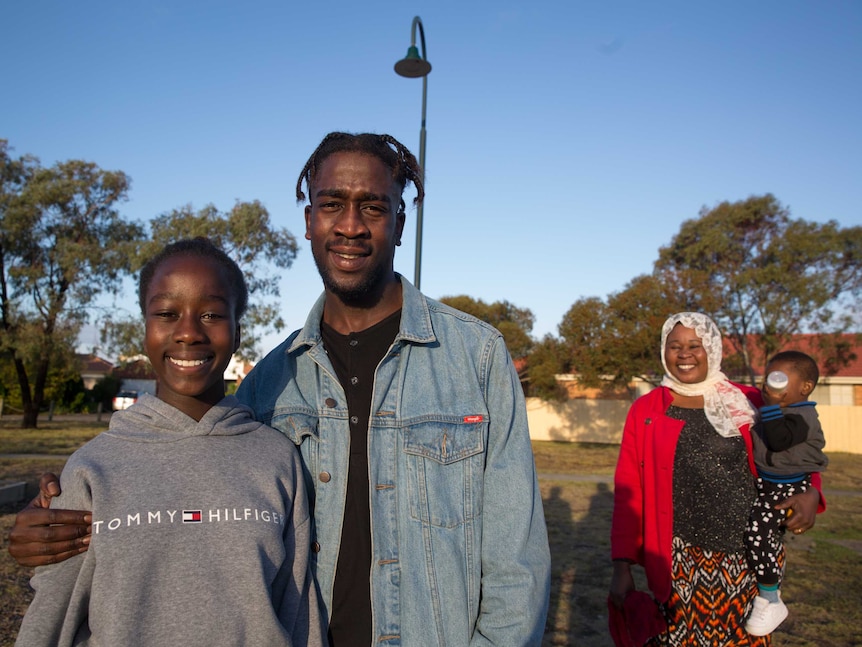 Kadiga watches on as Mohamed poses for a photo with his younger sister Monahil.