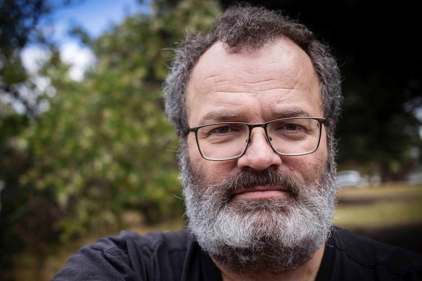 Middle aged man with beard and glasses and serious expression