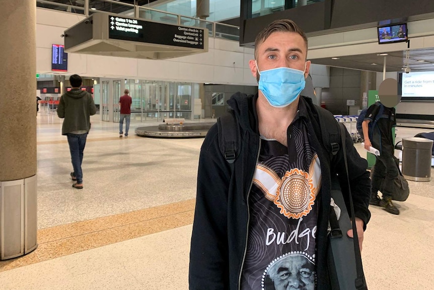 Professional boxer Sam Ah-See wearing a face mask as he stands in the baggage collection carousel area of the Brisbane airport.