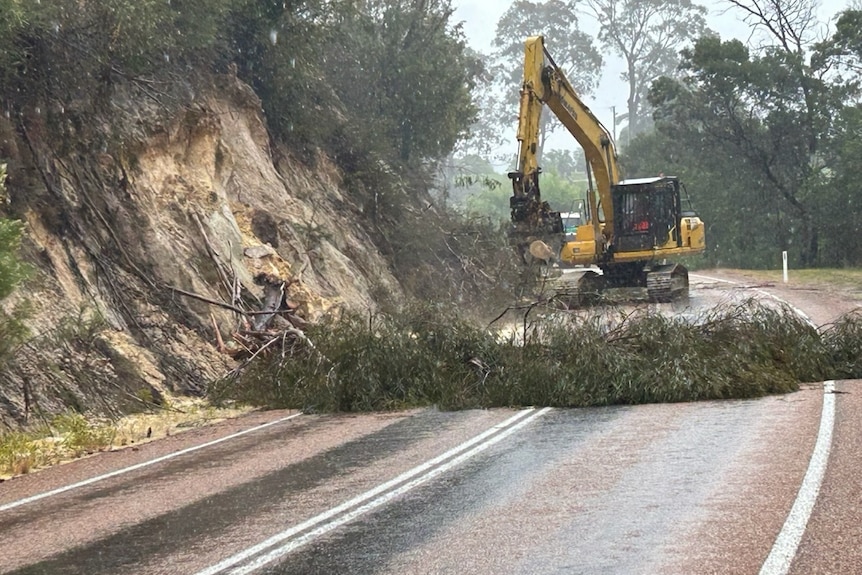 A digger clears up a landslide on a road near Mallacoota.