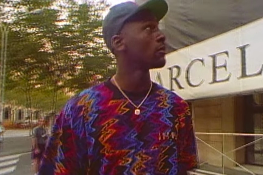 Michael Jordan wears a cap and a loud shirt on the street.