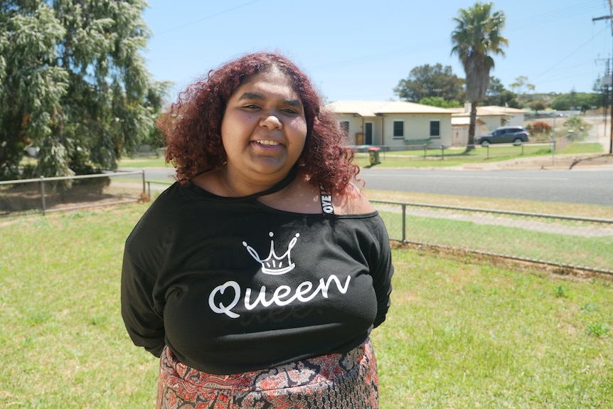 A woman wearing a shirt saying Queen on it 
