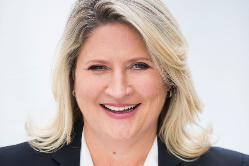 A woman in a suit smiles against a white background