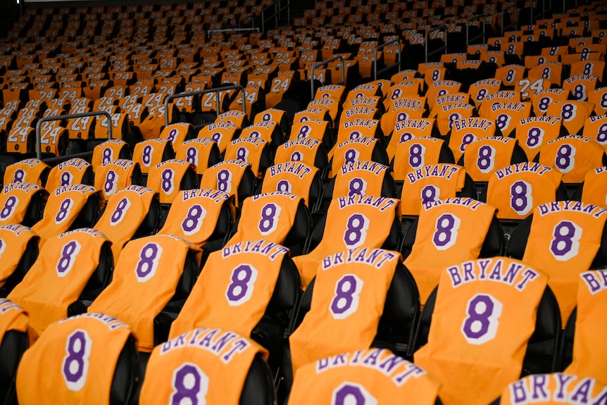 Jerseys with BRYANT 8 and 24 hang on chairs inside a sports stadium