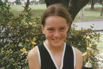 a young girl with brown hair wearing a sport uniform. 
