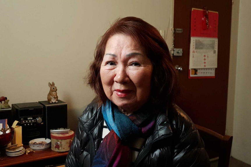 Helen Soo, wearing a scarf and jacket, looks into the camera.