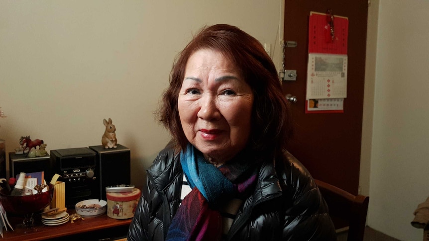 Helen Soo, wearing a scarf and jacket, looks into the camera.