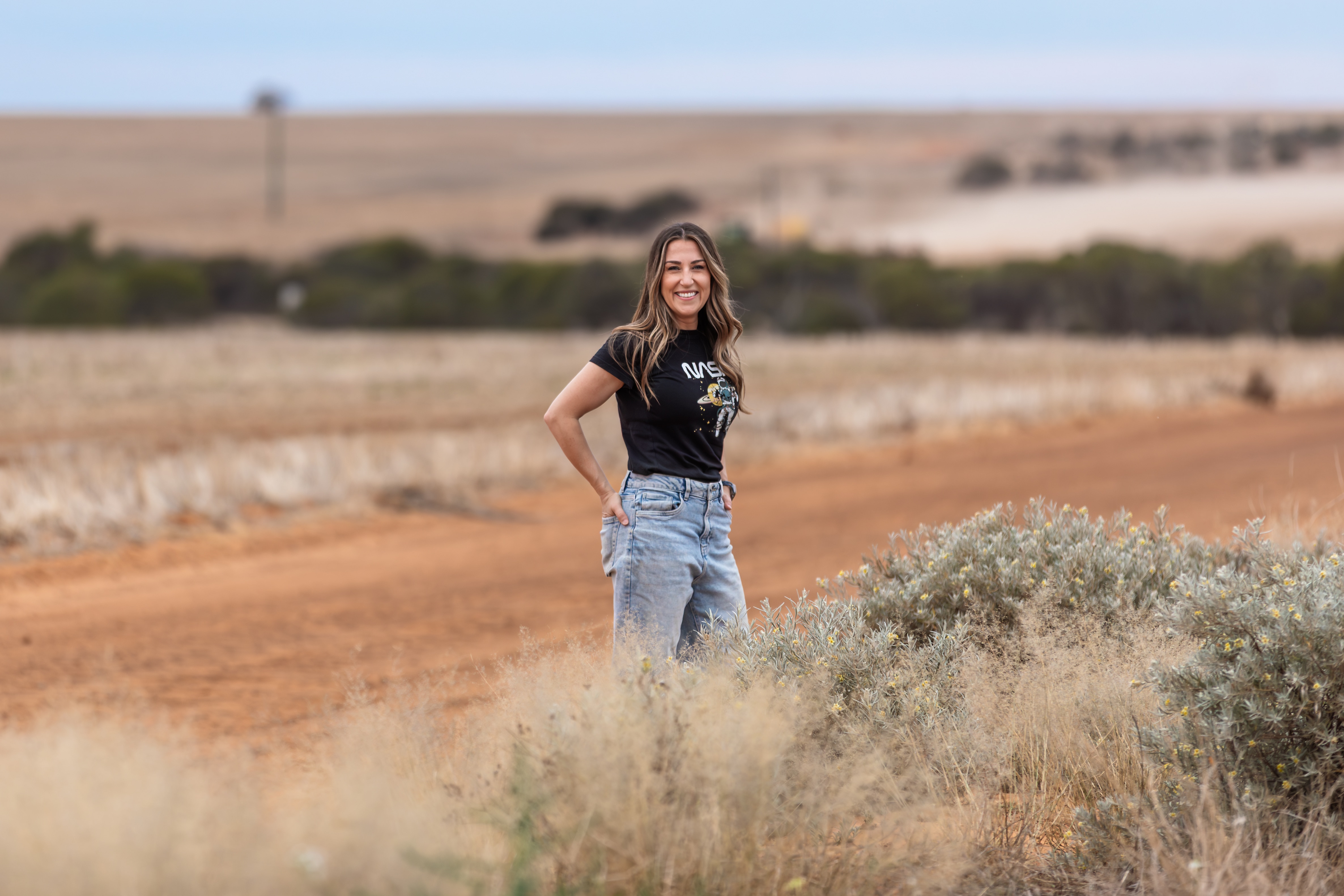 A woman wearing a NASA tshirt standing near a dirt road