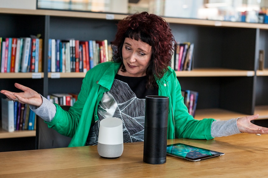 A woman raises her arms in confusion, while looking at three virtual assistant units.