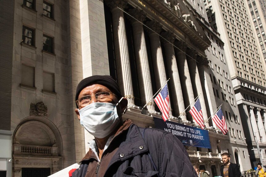 A man wears a medical mask as he walks past the New York stock exchange.