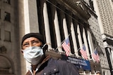 A man wears a medical mask as he walks past the New York stock exchange.