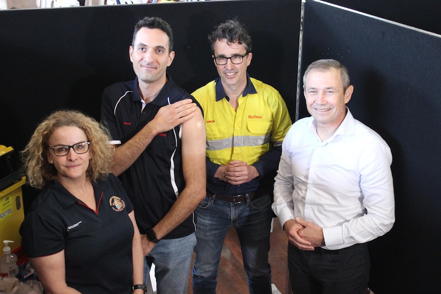 Three men and a woman. One man showing his vaccination arm. 