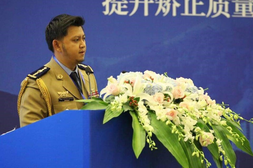 Cambodia prisons spokesman Nuth Savna speaking at a podium with flowers