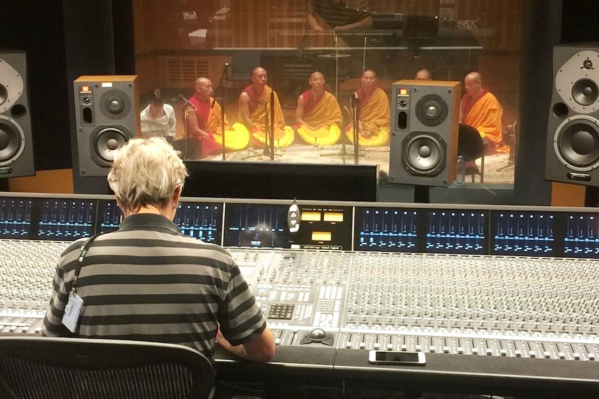A group of monks sitting crossed legged in a recording studio