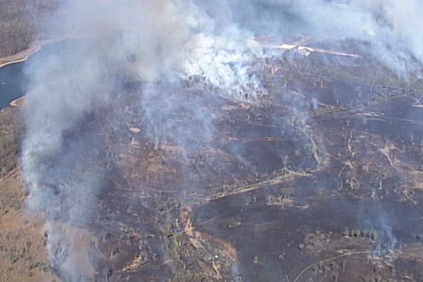 An aerial shot shows the nearby wivenhoe dam as smoke billows from several spot fires.