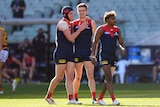 An AFL player stands as his teammate puts his arms around him in congratulation after a goal.