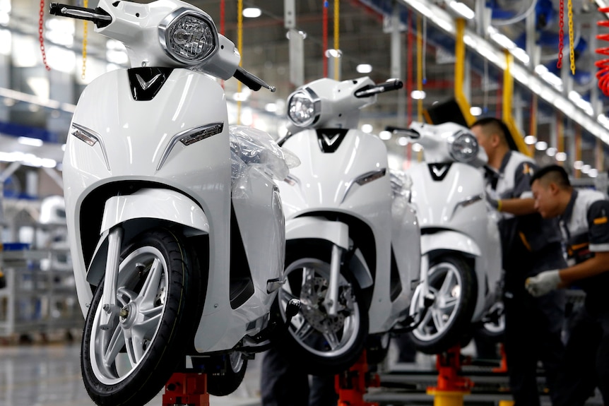 A production line of scooters on a factory floor.