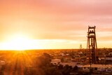 The sun sets behind a towering structure at a mine.