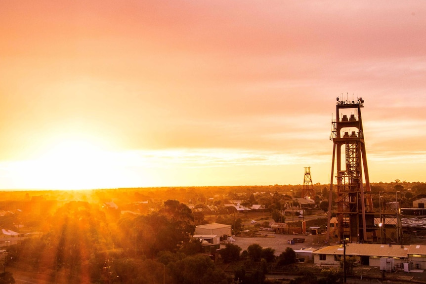 The sun sets behind a towering structure at a mine.