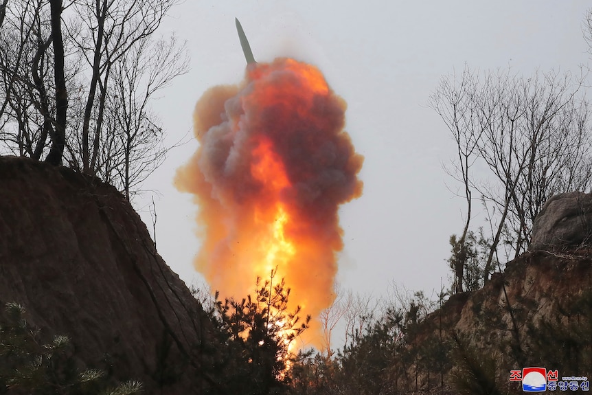 a missile is launch into the air with an explosion behind it