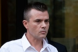 Igor Danchenko, wearing a white dress shirt with the sleeves rolled up, walks out of a courthouse.