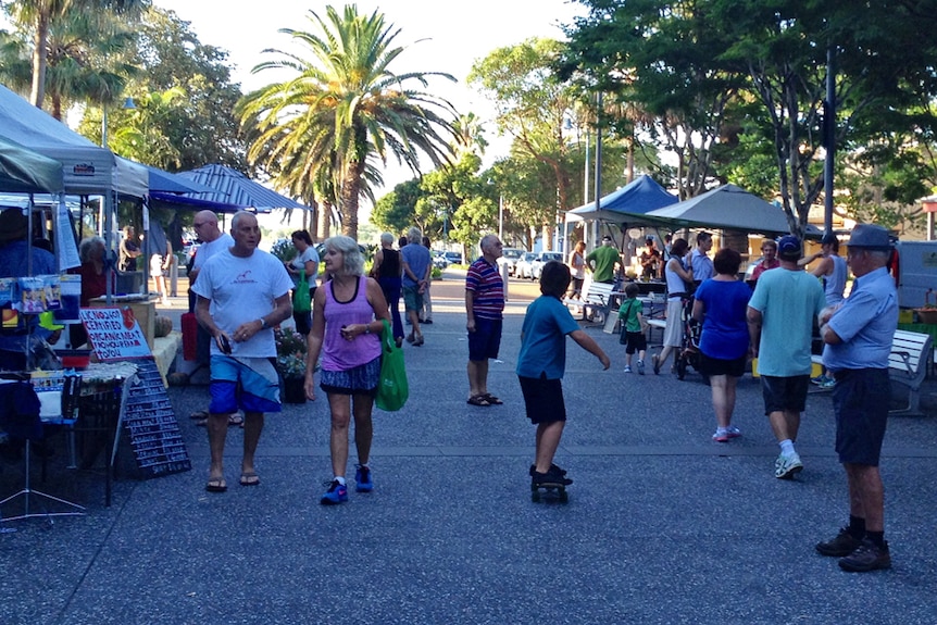 Skater and people walking through the produce markets in Port Macquarie.