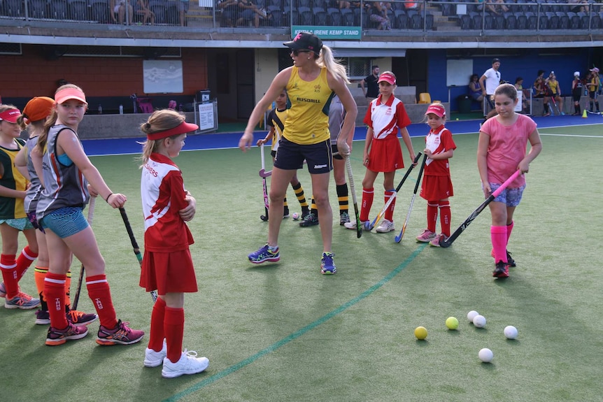 A Hockeyroo conducts training with a group of girls.