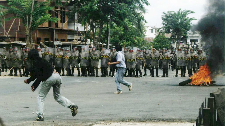 Protesting students throw stones at Indonesian riot police.