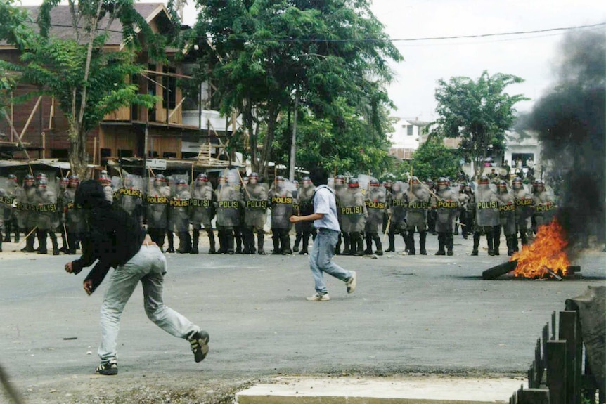 Protesting students throw stones at Indonesian riot police.