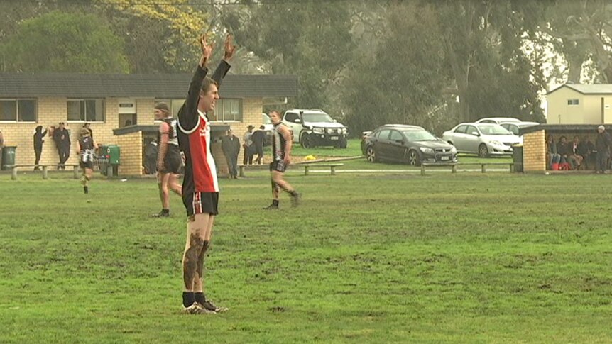 A player has his hands up for the ball and is getting wet from heavy rain