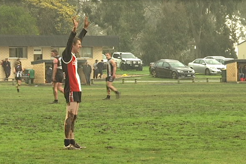 A player has his hands up for the ball and is getting wet from heavy rain