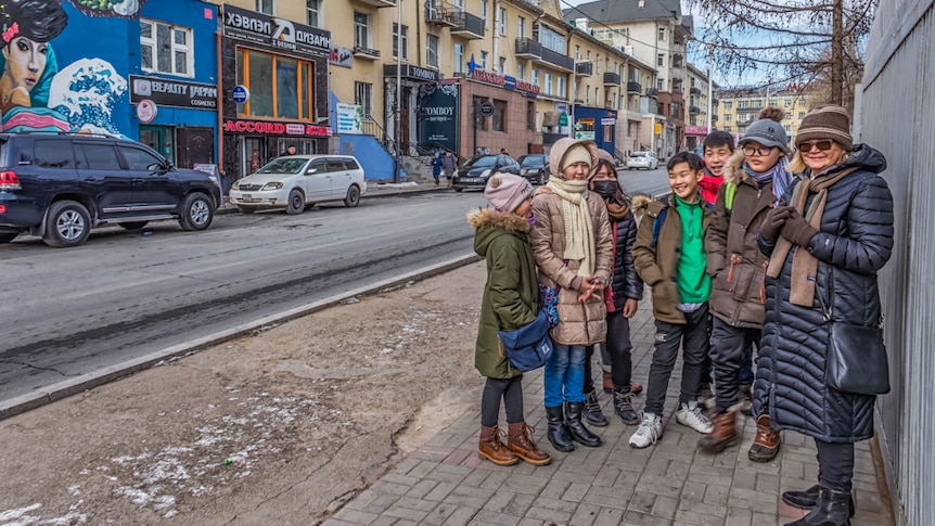 Volunteer Susan Wilson standing on a street with a group of Mongolian teenagers