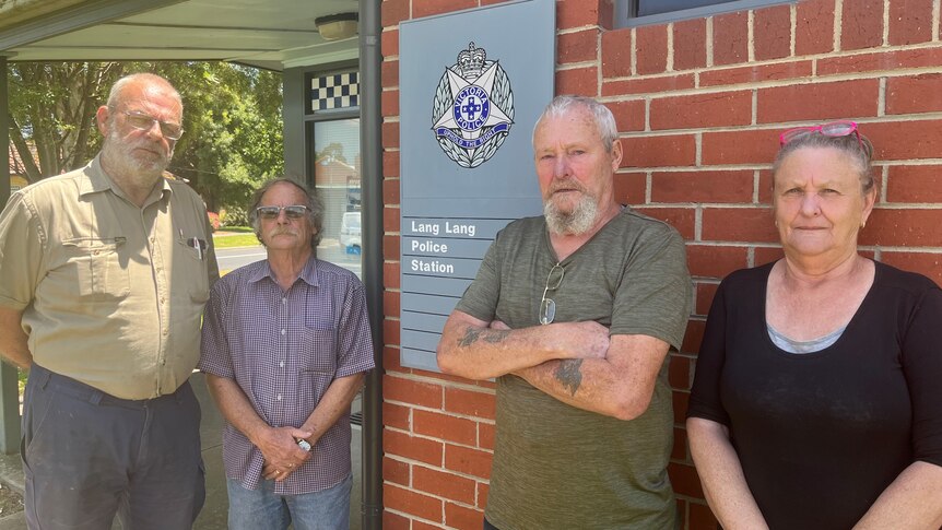 Four people stand by the front of a police station