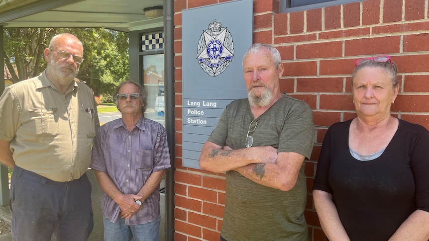 Four people stand by the front of a police station